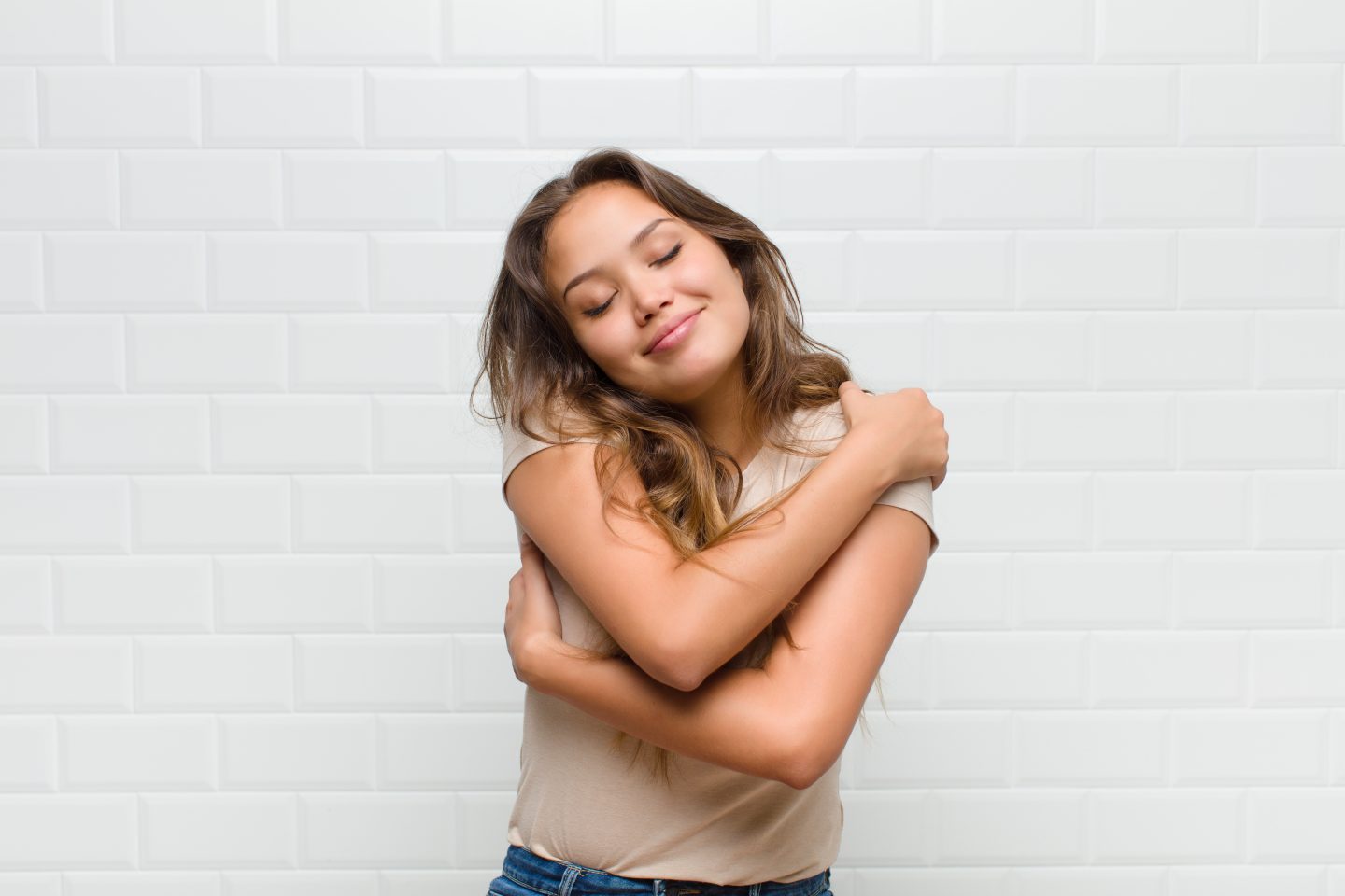 Mulher se abraçando com expressão de amor próprio.